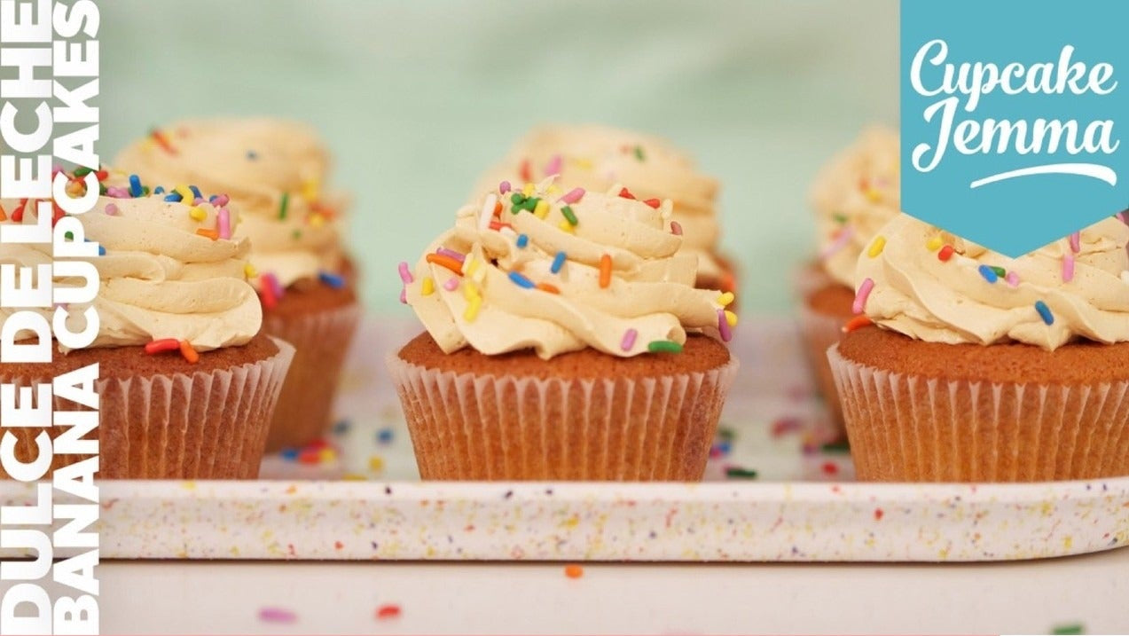 Banana Dulce de Leche Cupcakes topped with buttercream and sprinkles on a tray recipe by Cupcake Jemma