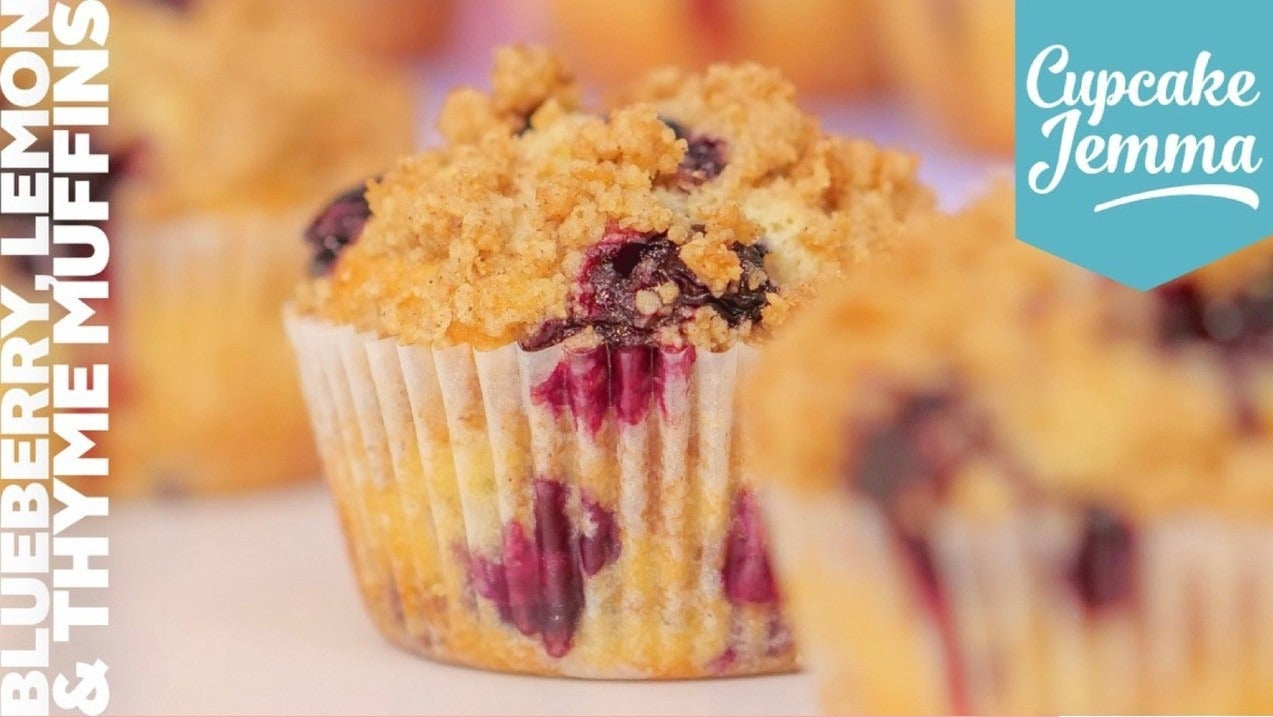 Close-up of a blueberry lemon and thyme muffin with crumbly streusel topping by Cupcake Jemma recipe.