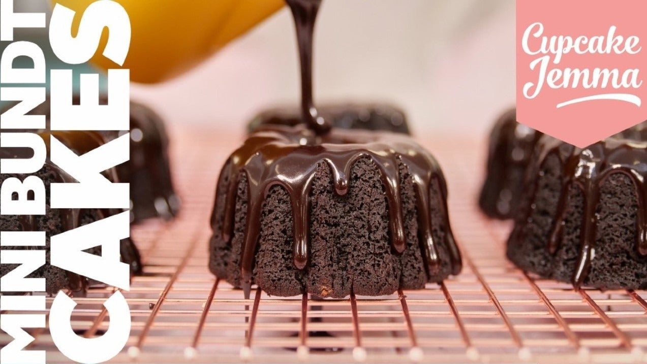 Mini chocolate bundt cake with glossy chocolate sauce drizzled on top on a cooling rack by Cupcake Jemma