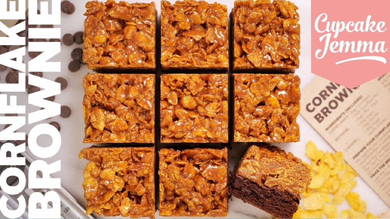 Squares of crunchy cornflake brownies with one piece showing chewy chocolate interior alongside recipe ingredients text