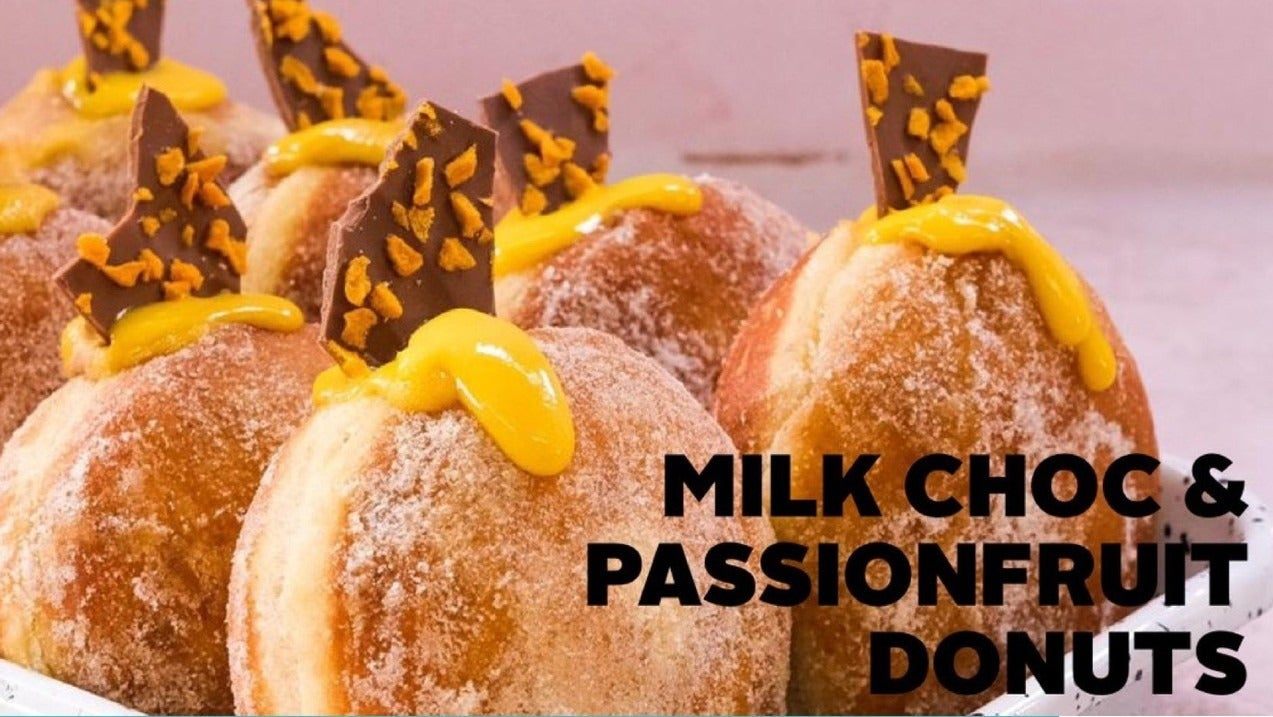 Close-up of Dane's Passionfruit and Milk Chocolate Donuts topped with chocolate bark and passionfruit glaze on a tray