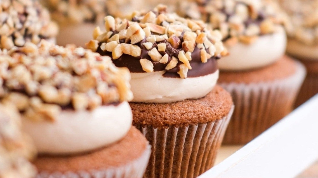 Close-up of Ferrero Rocher Cupcakes topped with frosting, chocolate, and chopped hazelnuts, with recipe ingredients list below