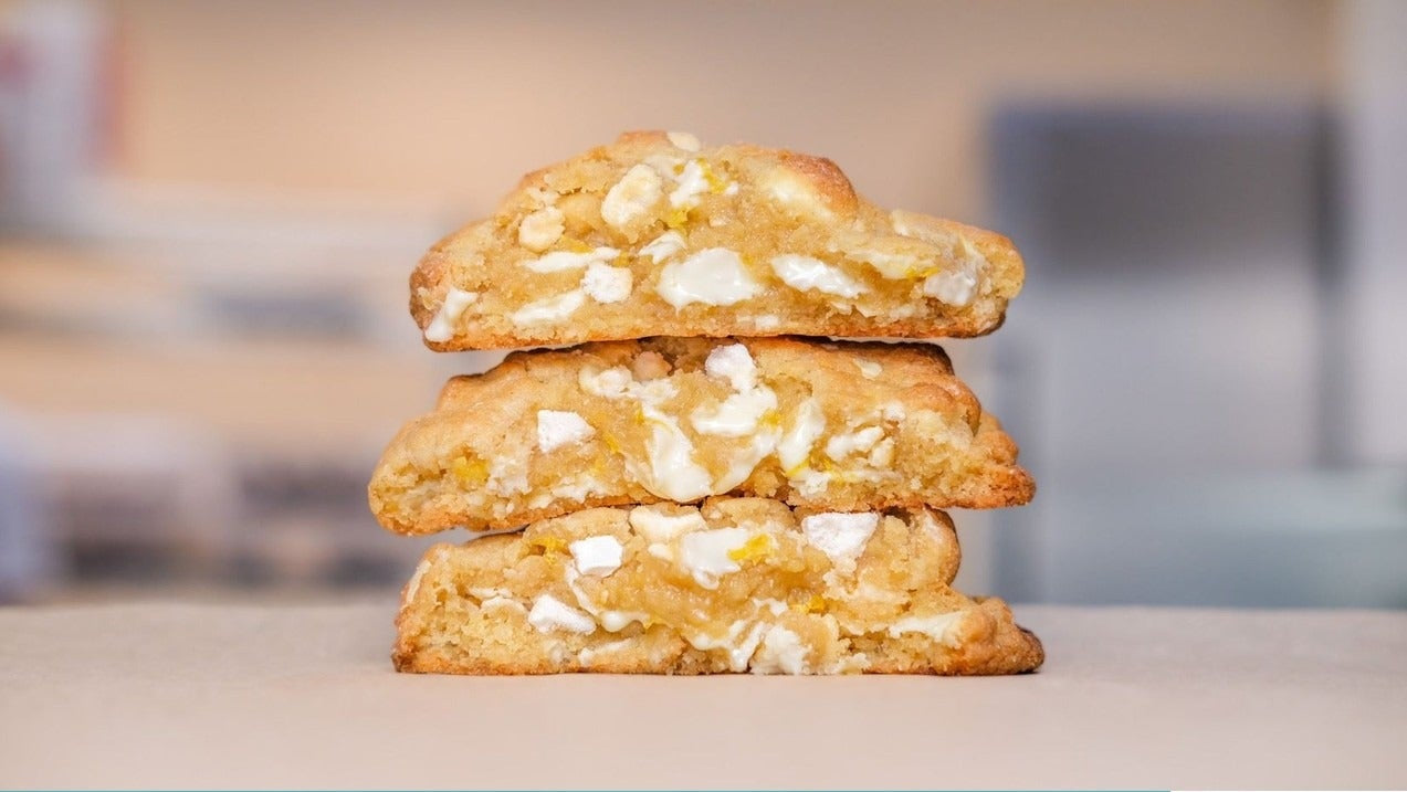Stacked lemon New York cookies showing white chocolate and meringue pieces, part of a downloadable baking recipe.