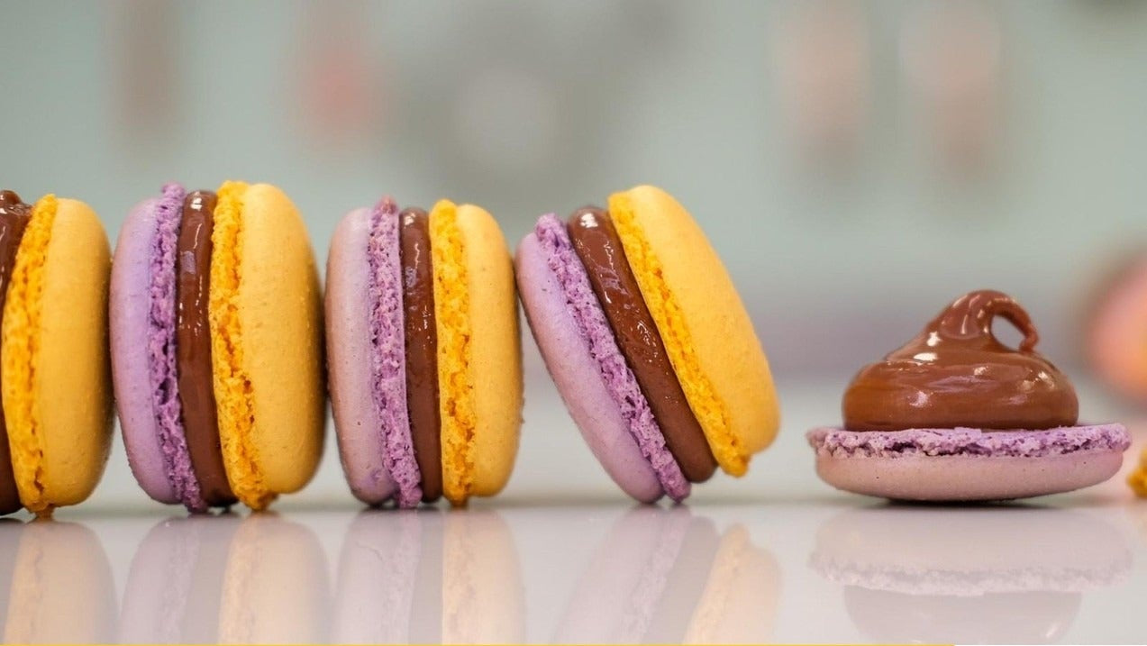 Yellow and purple macarons filled with milk chocolate ganache from the Milk Chocolate & Passionfruit Macarons downloadable recipe