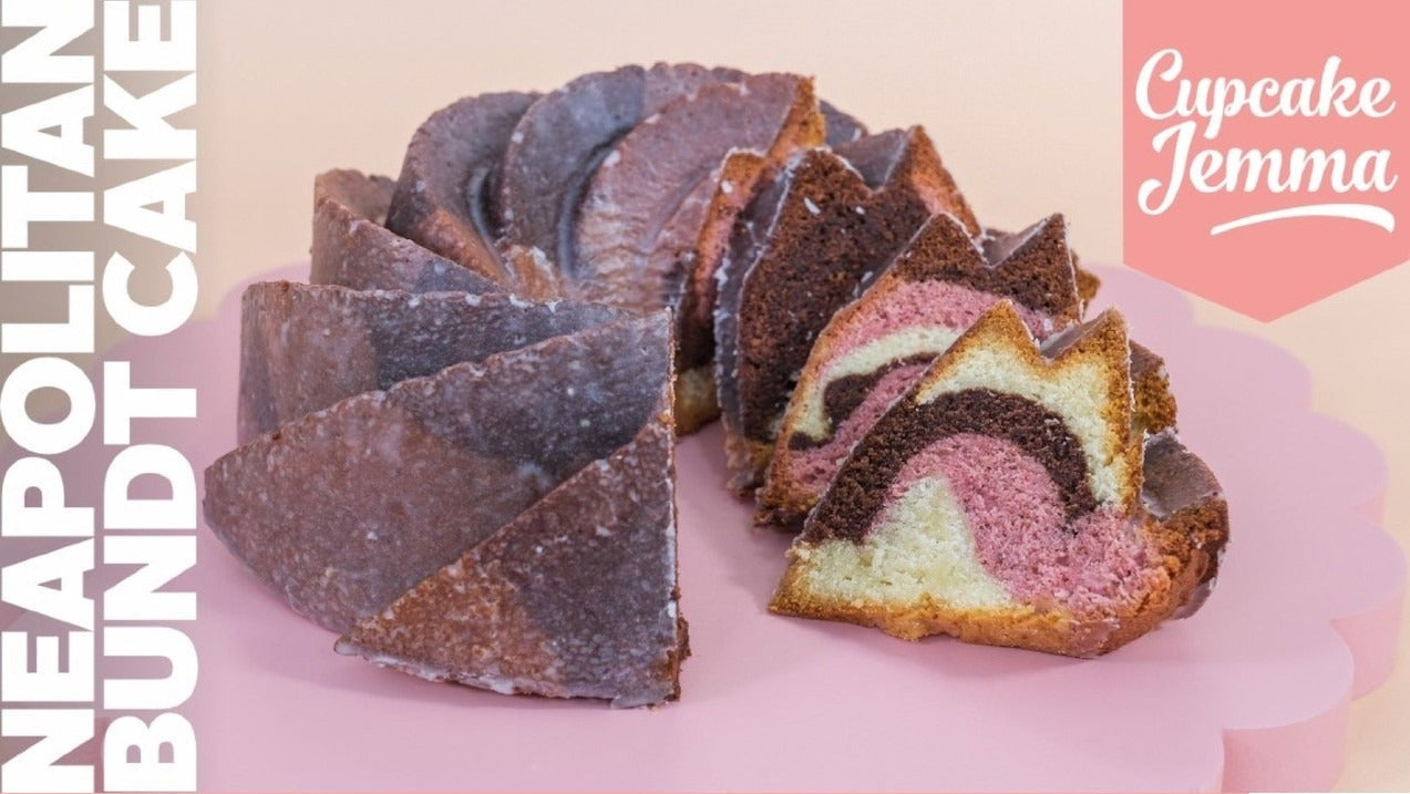 Sliced Neapolitan Bundt Cake showing chocolate vanilla and strawberry layers with recipe ingredients by Cupcake Jemma