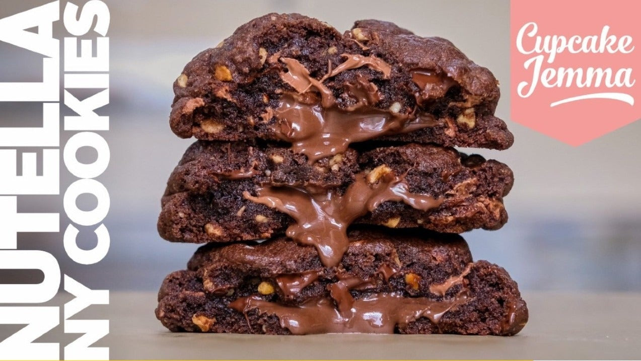 Stack of three gooey Nutella New York Cookies with melted chocolate chips and hazelnuts visible inside the warm cookies