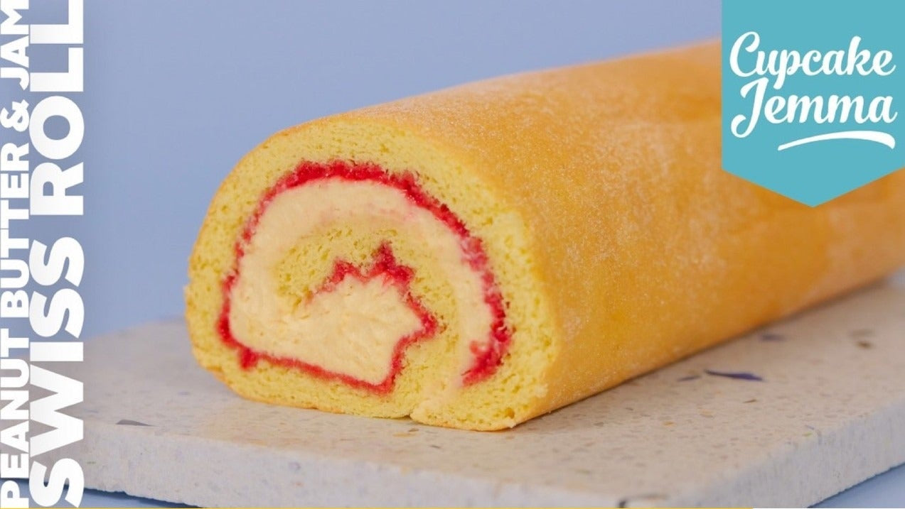Close-up of a Peanut Butter & Jam Swiss Roll by Cupcake Jemma showcasing creamy peanut butter and strawberry jam swirl inside sponge cake.