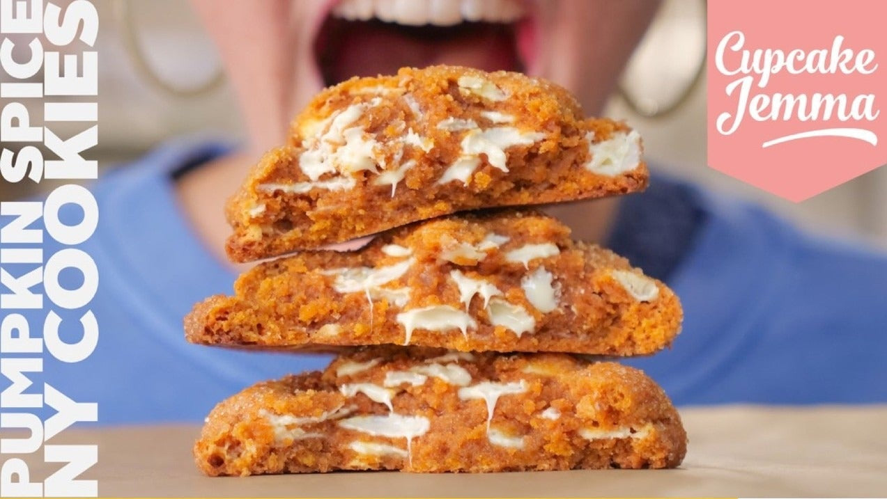 Stacked Pumpkin Spice New York Cookies with visible white chocolate chunks and ingredients list beside them