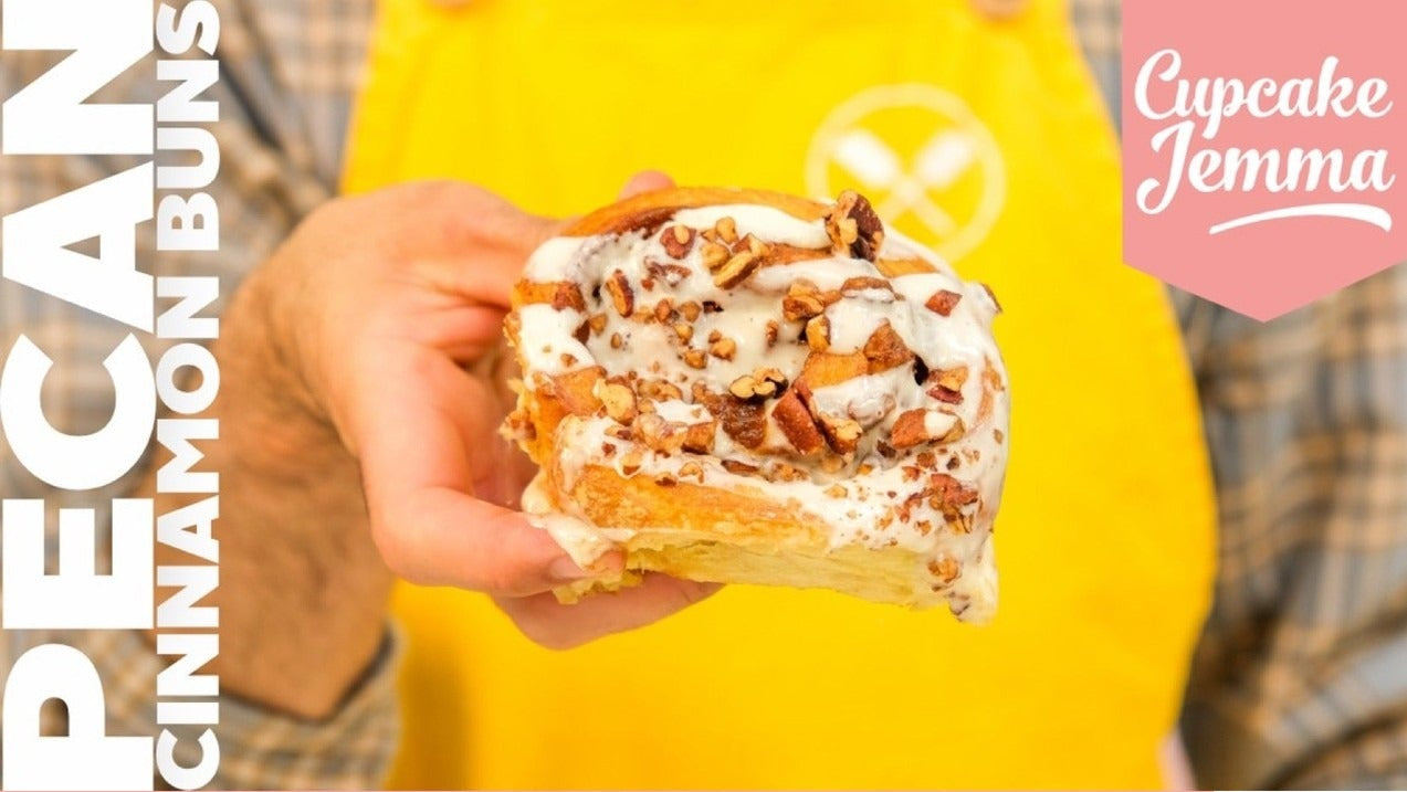 Close-up of a Vanilla Pecan Cinnamon Roll topped with cream cheese glaze and chopped pecans by Cupcake Jemma