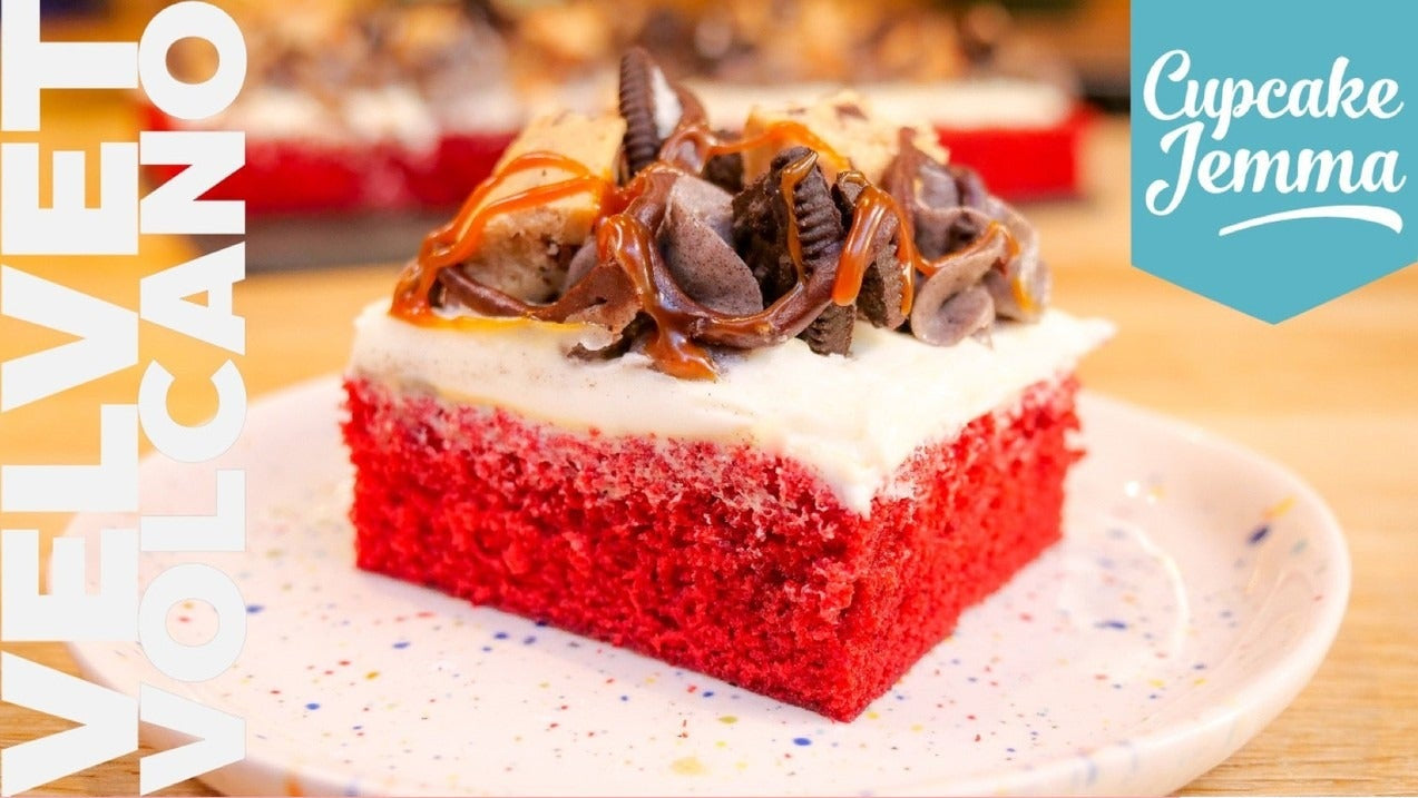 Close-up of a rich Velvet Volcano Sheet Cake slice topped with cookie dough, oreo pieces, caramel, and ganache from Cupcake Jemma recipe.