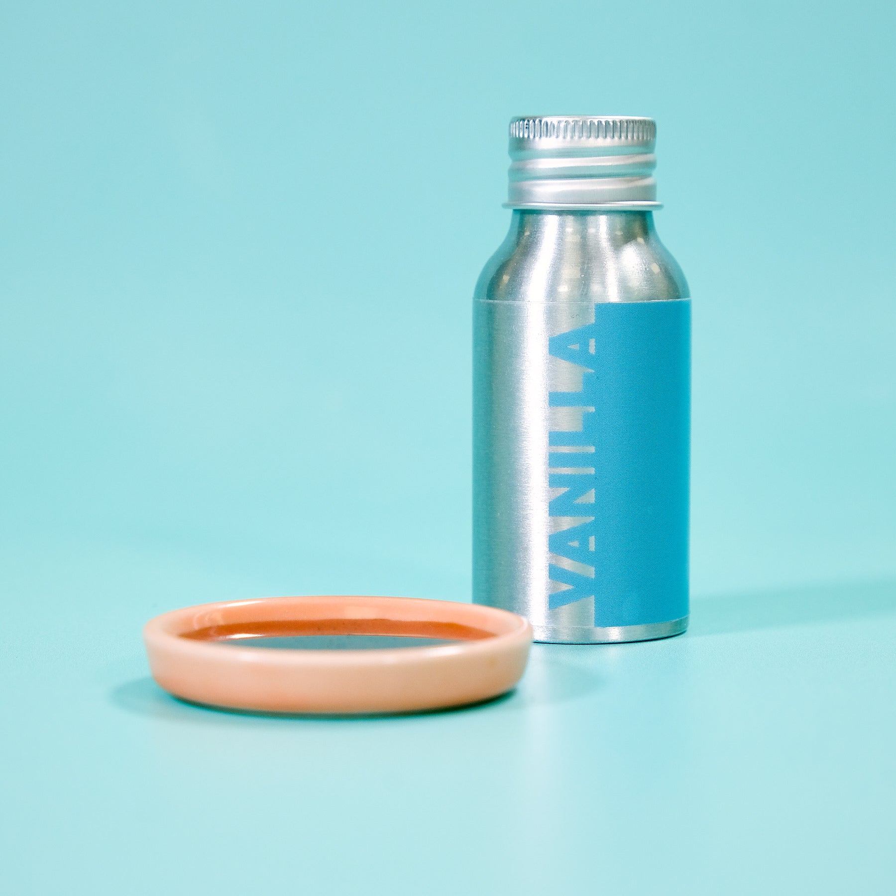 Vanilla Extract 50ml bottle on blue background next to small round ceramic dish for baking and recipes