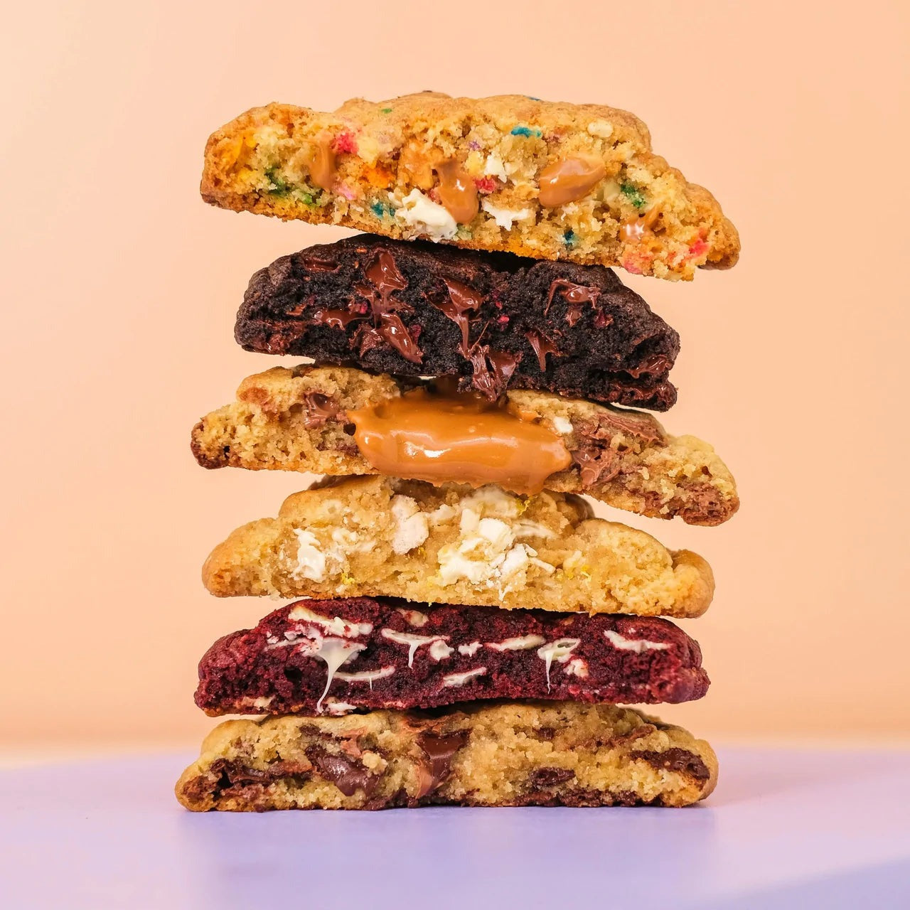 Stack of freshly baked New York Cookies with various fillings and textures on a light background