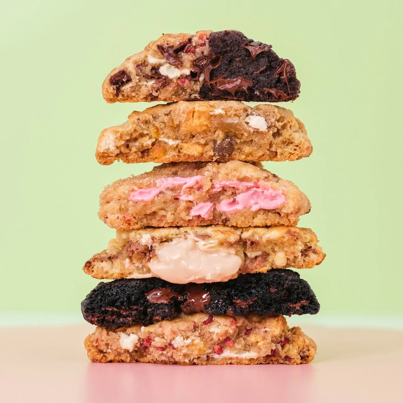 Stack of freshly baked New York cookies with various fillings and textures on a pastel background