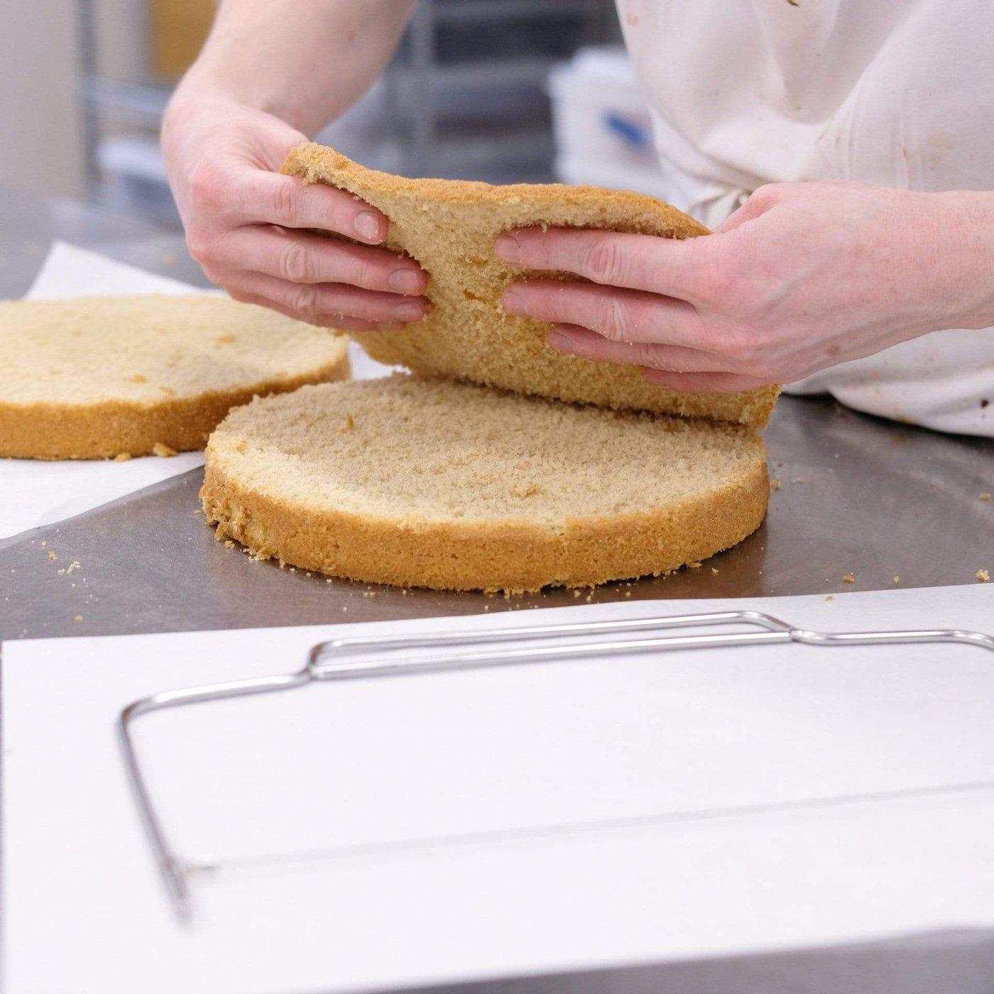 Person holding evenly sliced sponge cake layers with a cake leveller wire tool on table