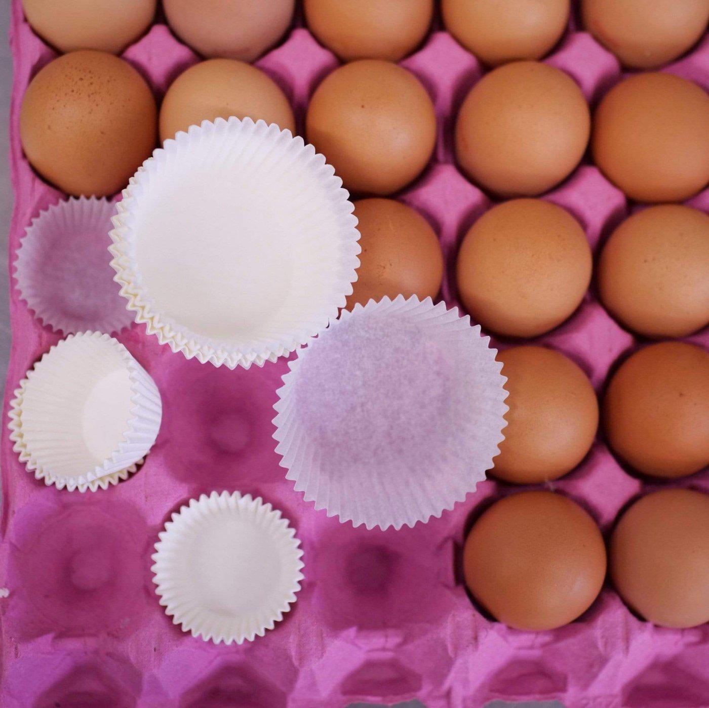 Cupcake Cases Regular white greaseproof paper cases on a tray of brown eggs for baking by Cupcake Jemma